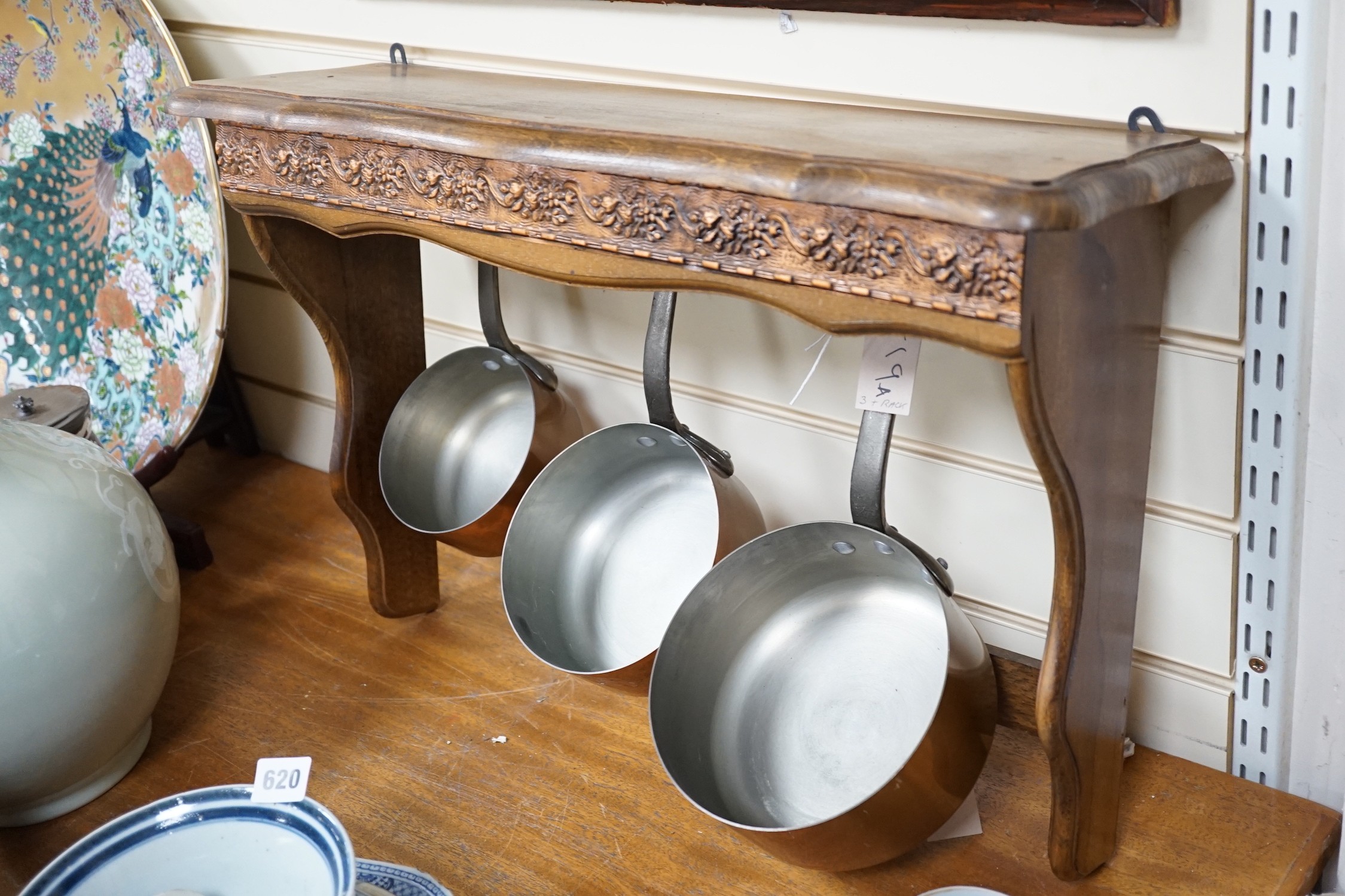 A set of three French copper saucepans, pendant from rack, 57cm wide